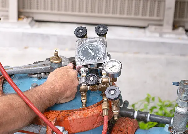 Technician adjusting pressure gauges on a backflow testing device during an annual inspection at a commercial property in Orange County, California.
